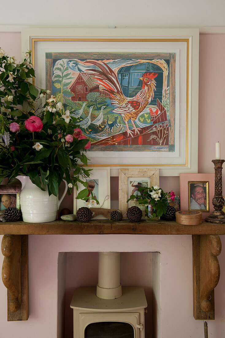 Holzmantel mit Kunstwerken und Schnittblumen mit Holzofen in einem modernen Haus in Lewes, East Sussex, England, UK