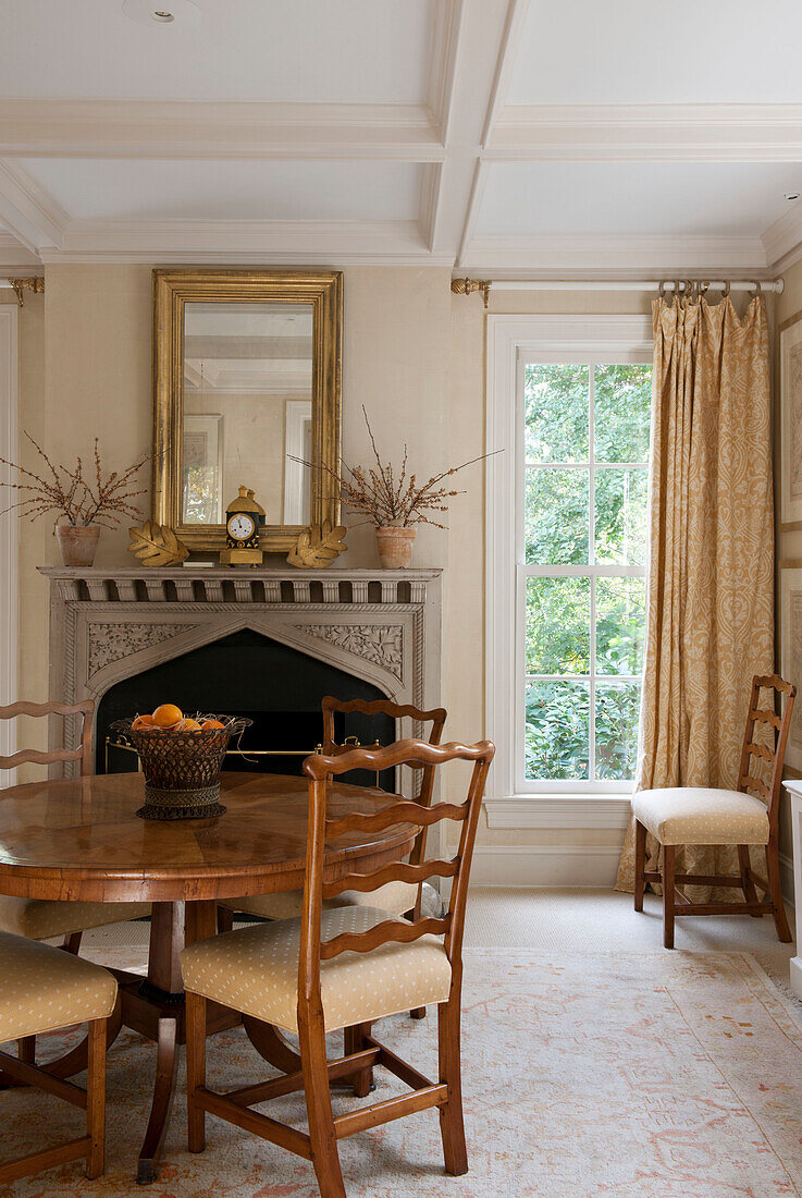 Polished wood dining table and gilt framed mirror in Washington DC home,  USA