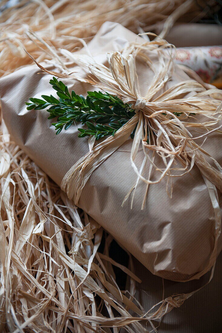 Brown wrapping paper and straw,  gift wrapped Christmas present in Benenden cottage,  Kent,  England,  UK