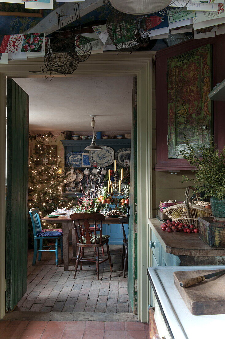 Karten hängen in der Küche mit Blick durch die Türöffnung auf den für das Weihnachtsessen gedeckten Tisch in Benenden cottage, Kent, England, UK