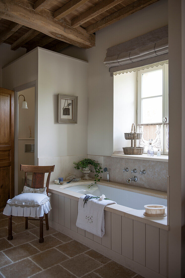 Stuhl neben der Badewanne am Fenster in einem Bauernhaus mit Balken in der Dordogne Perigueux Frankreich