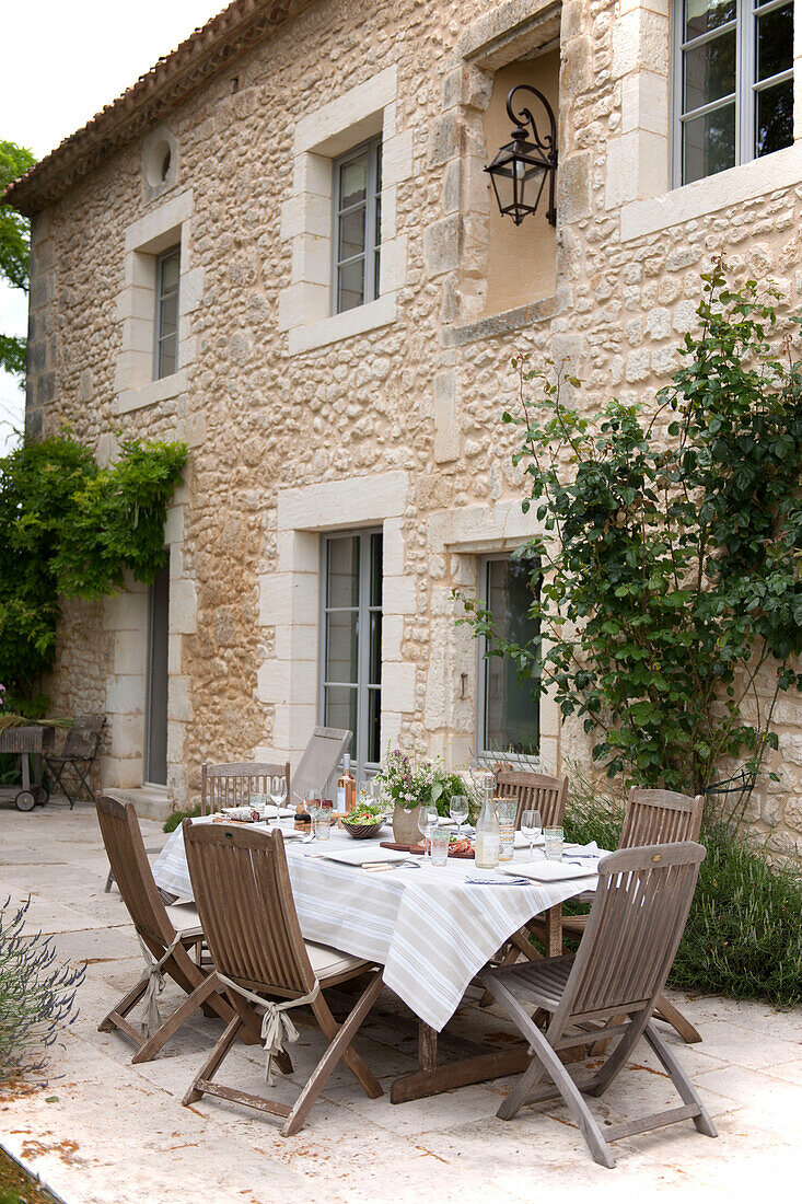 Wooden chairs at table on terraced exterior of Dordogne farmhouse  Perigueux  France