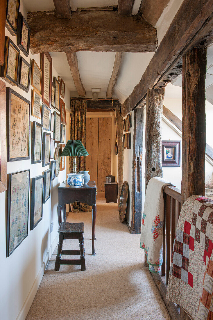 Bilderwand und Patchwork-Decken mit Balkendecke in einem Bauernhaus in Ashford, Kent, Großbritannien