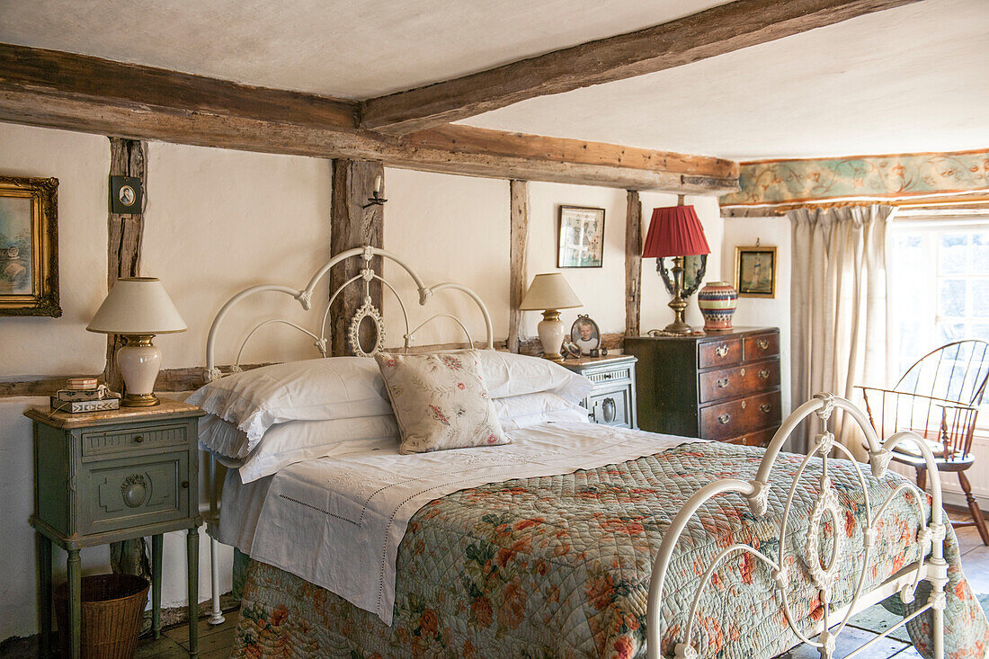 Bett mit Metallrahmen und geblümter Steppdecke in einem Bauernhaus in Ashford, Kent, Vereinigtes Königreich