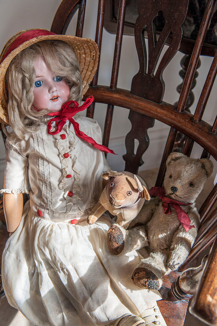 Antique doll with soft toys on vintage wooden chair in Ashford farmhouse  Kent  UK
