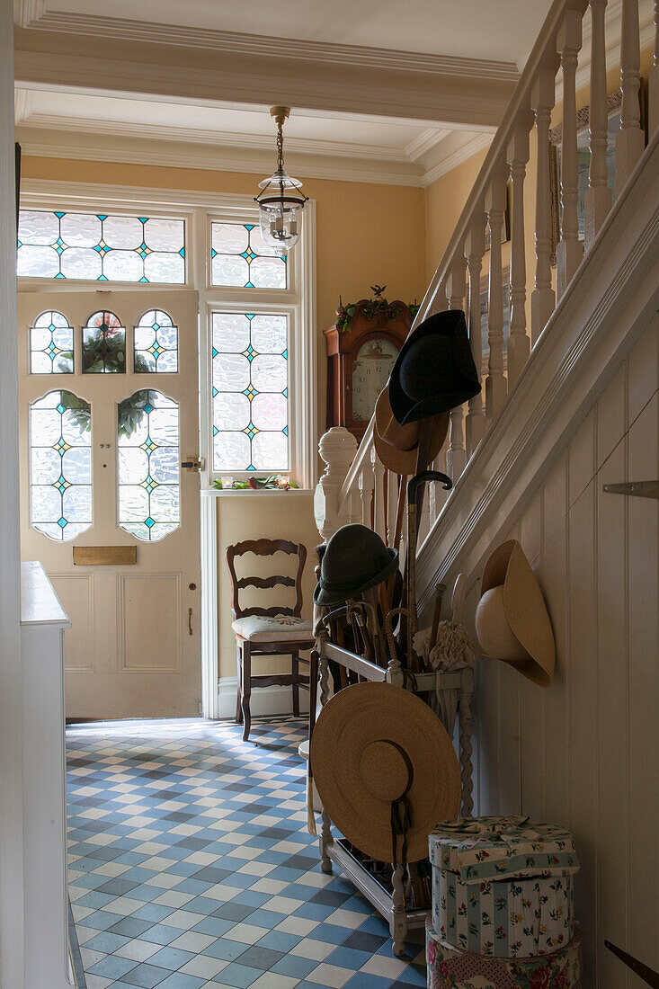 Hats and walking sticks in tiled hallway of London home with stained glass front door and window  England  UK
