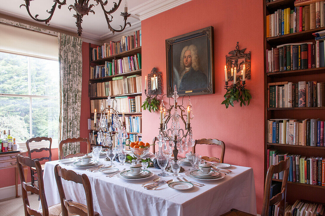 Esstisch mit Bücherregal und Glaskandelabern in einem Londoner Haus England UK