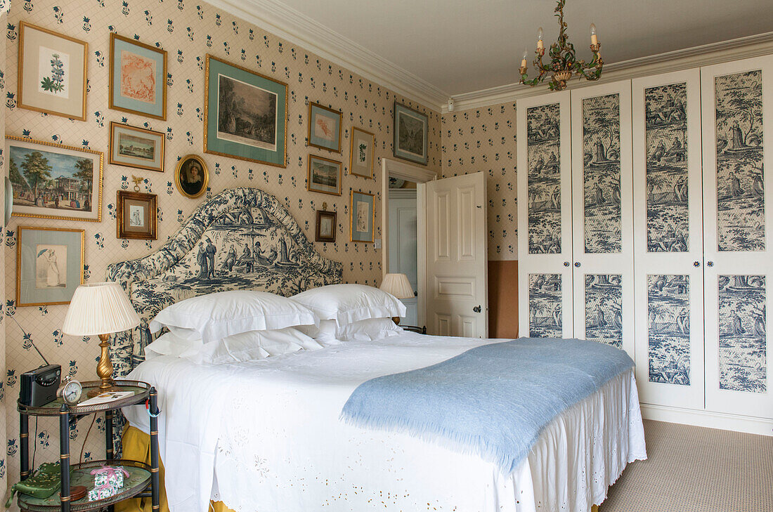Toile de jouy headboard with matching papered wardrobe and framed artwork in London bedroom  England  UK