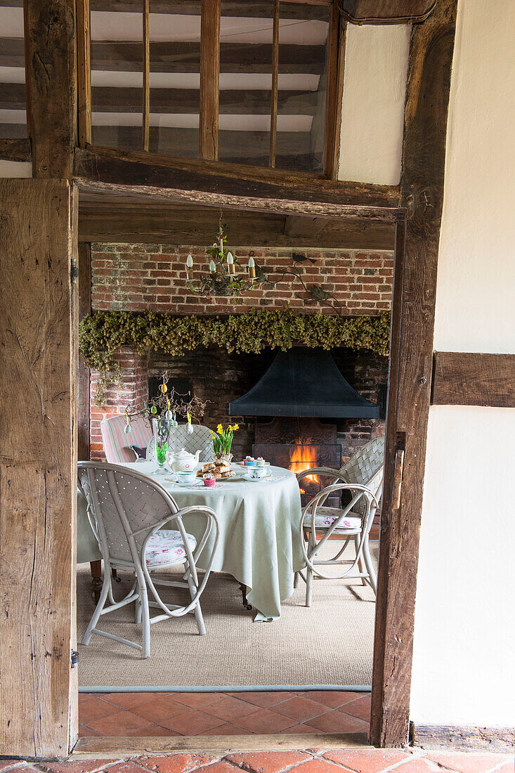 Blick durch die modernisierte Tür mit Holzrahmen auf den Tisch am Kamin in High Halden cottage Kent England UK