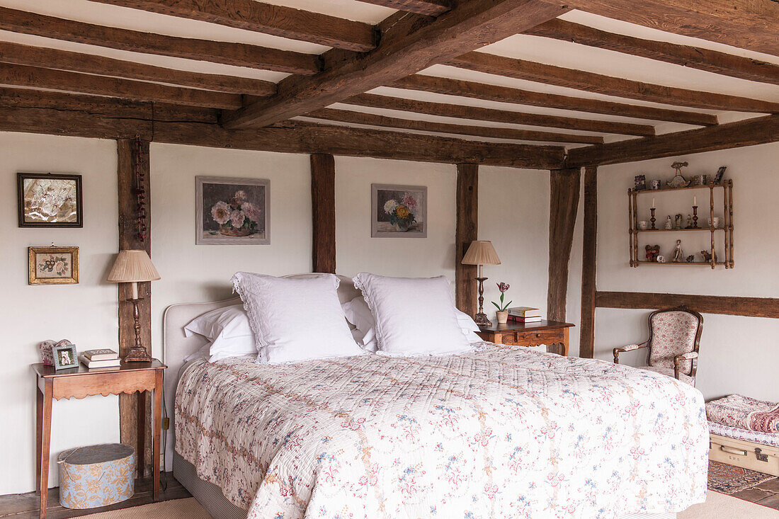 White pillows on quilted double bed below beamed ceiling in High Halden cottage  Kent  England  UK