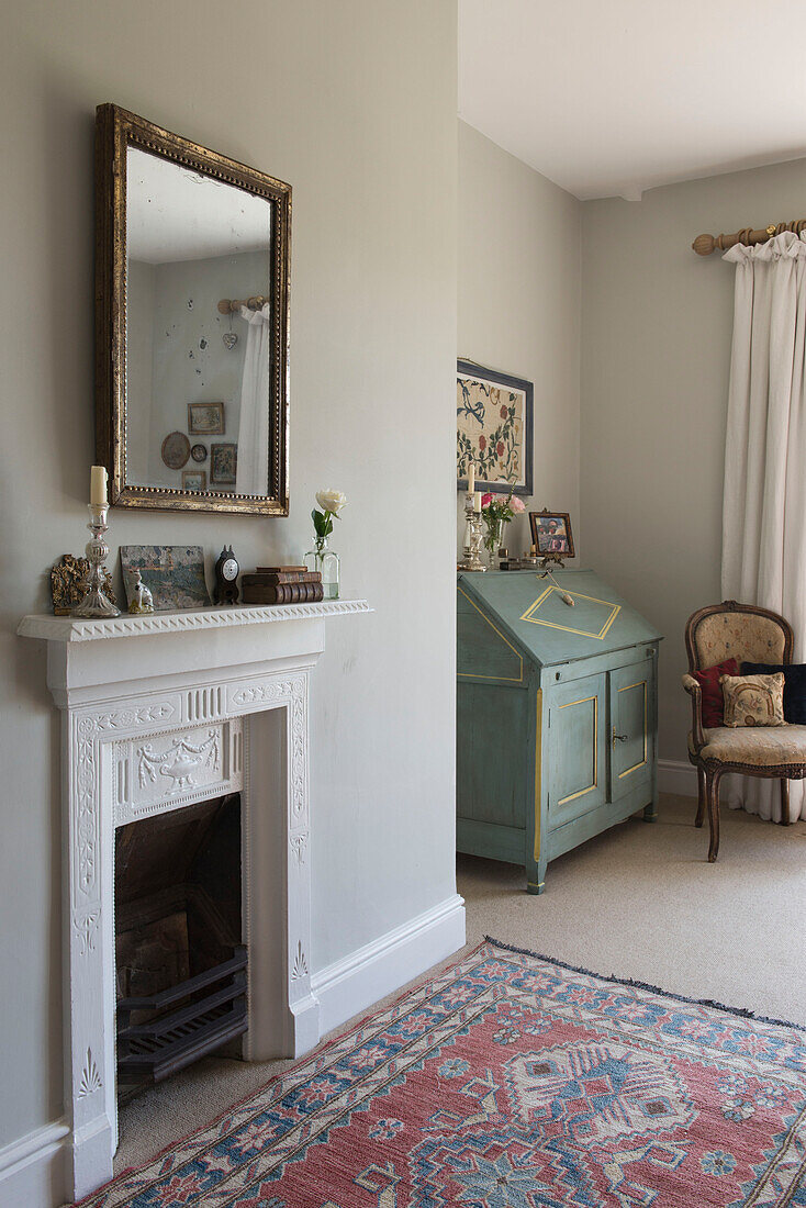 Vergoldeter Spiegel über dem Kamin mit Schreibtisch und gemustertem Teppich in East Barsham cottage Norfolk England UK
