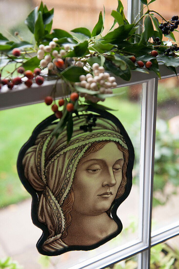 Mistelblätter und Beeren mit Buntglasfigur im Fenster des Londoner Hauses England UK