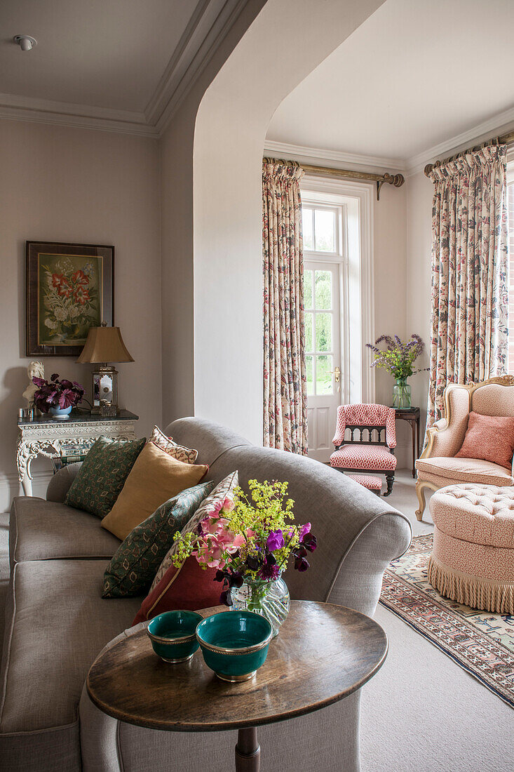 Wohnzimmerdetail mit grauem Sofa und rosa Stühlen