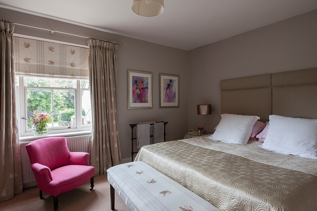 Double bedroom in neutral decor with bright pink armchair