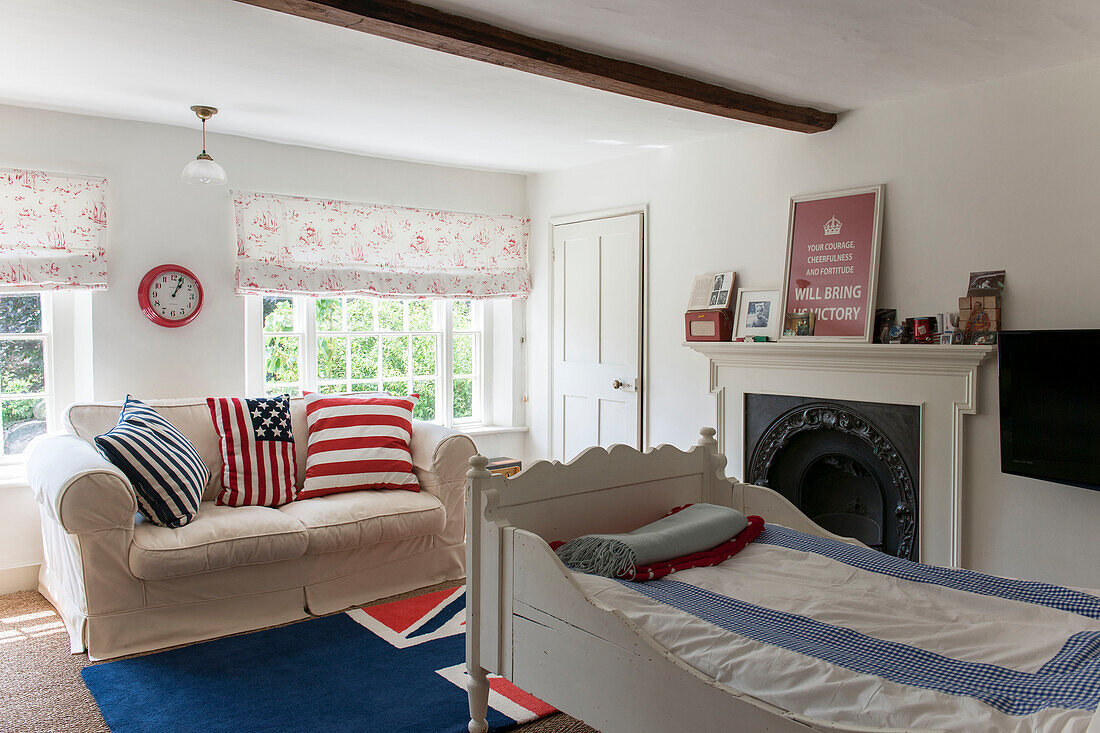 Zweisitzer-Sofa und Tagesbett mit gerahmtem Kunstwerk über dem Kamin im Schlafzimmer eines Hauses in Kent, England, Vereinigtes Königreich