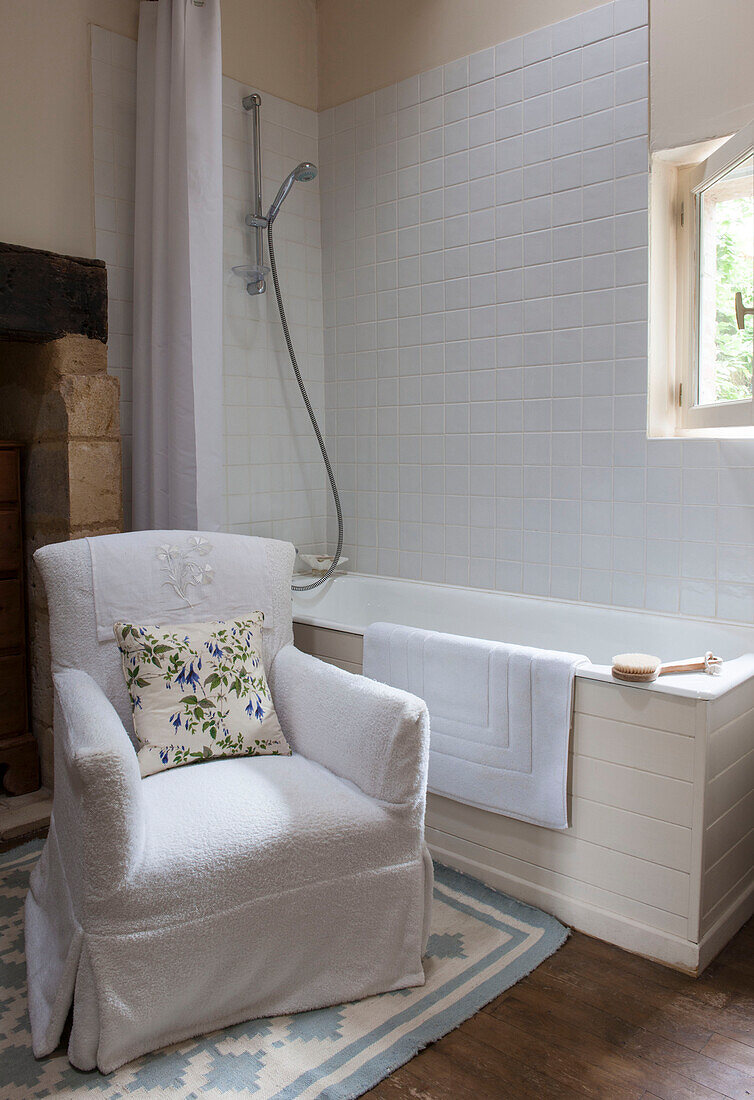 Weißer Sessel und Badewanne im gefliesten Badezimmer eines Landhauses in der Dordogne in Frankreich