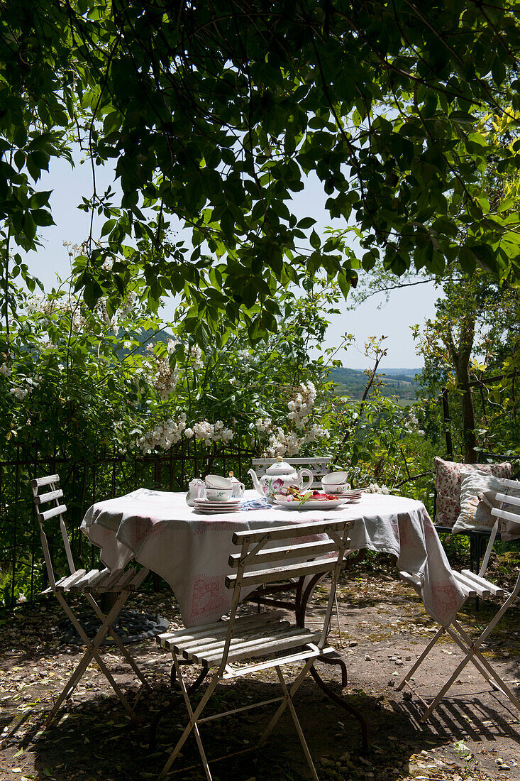 Teekanne und Tassen auf einer sonnenbeschienenen Terrasse in der Dordogne Frankreich