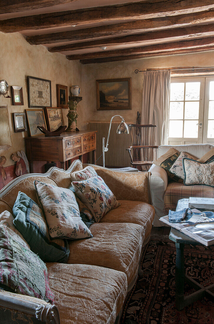 Kissen auf Sofas mit hölzerner Kommode in einer umgebauten Scheune mit Balken in Lotte et Garonne, Frankreich