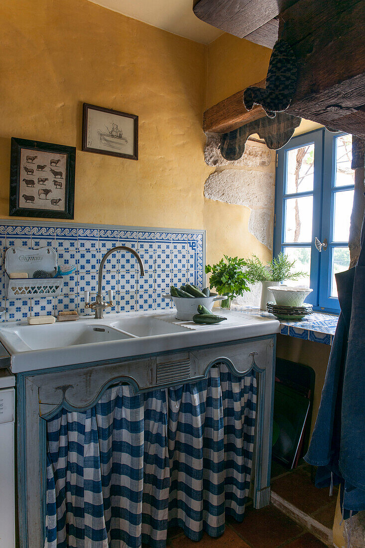 Gefliestes Waschbecken mit gelber Wand am Fenster in einer umgebauten Scheune in Lotte et Garonne, Frankreich