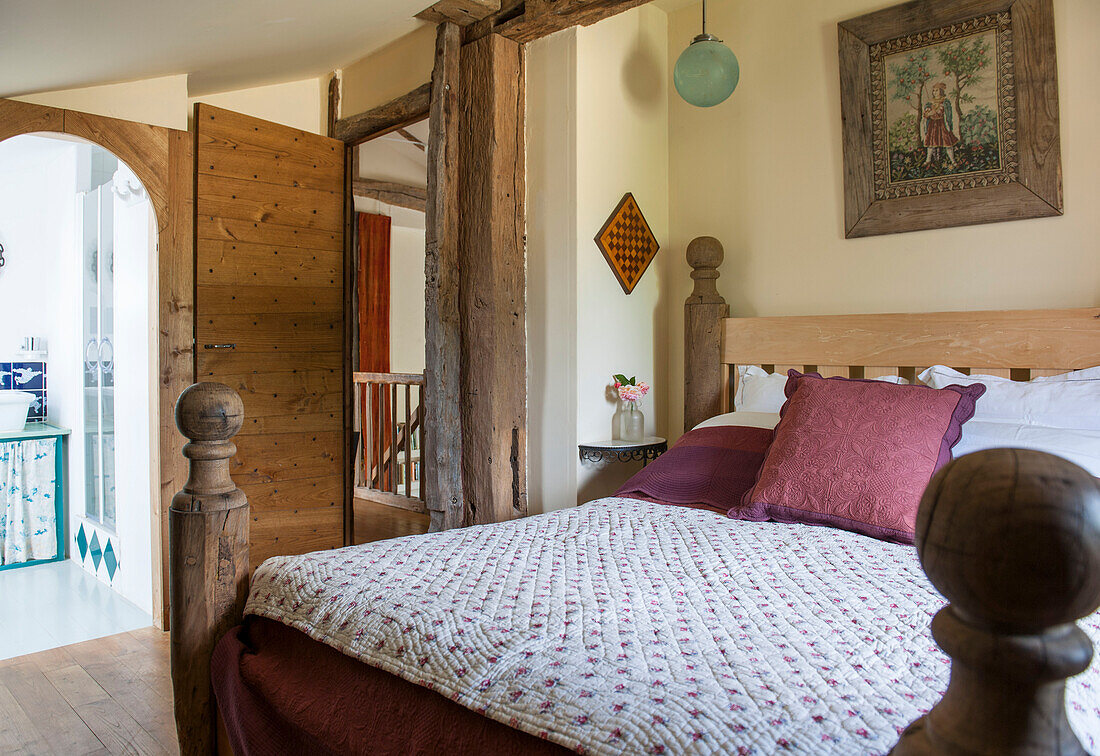 Quilted cover on wooden bed with framed artwork in Lotte et Garonne farmhouse  France