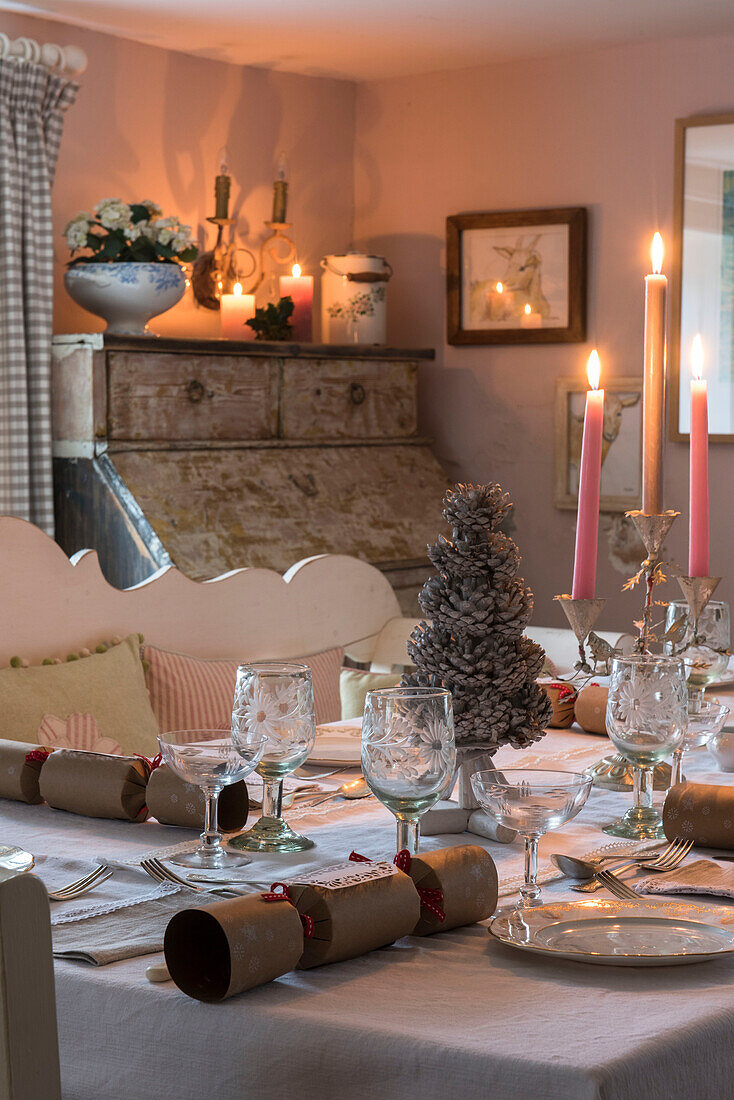Vintage glasses and lit candles on dining table at Christmas in Grade II listed cottage  Kent