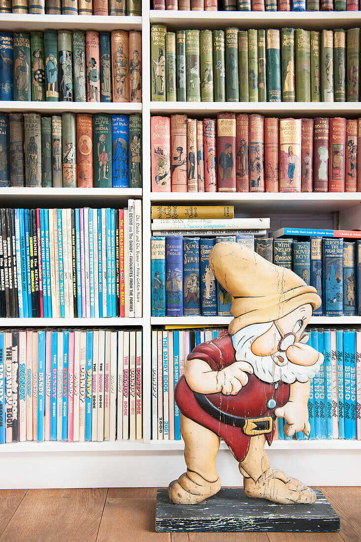 Cut-out dwarf with vintage books on shelving in Norfolk coastguards cottage  England  UK
