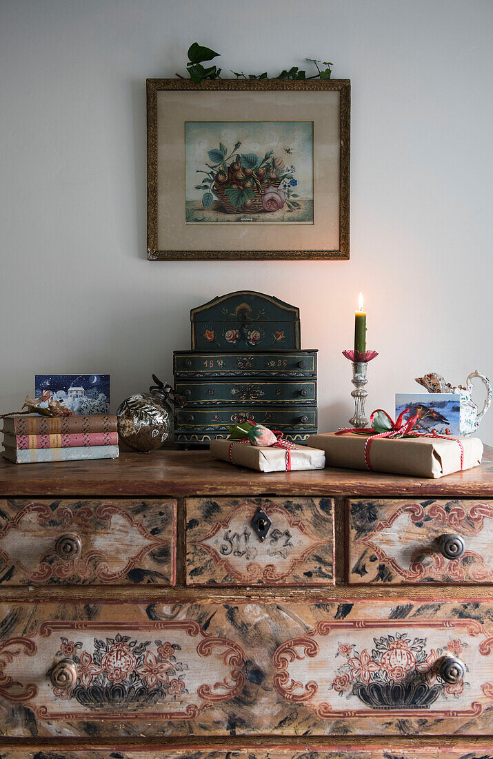 Lit candle and jewellery box on wooden chest with artwork in East Sussex coach house  England  UK
