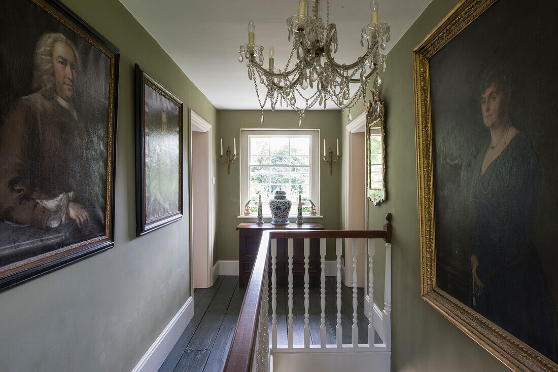 Large artworks and glass chandelier in landing of 18th century Surrey home  England  UK