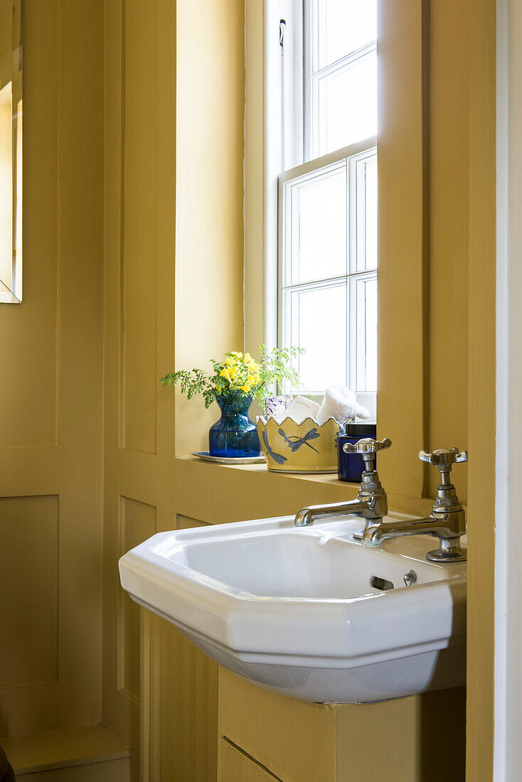 Keramisches Waschbecken im gelb getäfelten Badezimmer eines Hauses in Surrey, England, 18