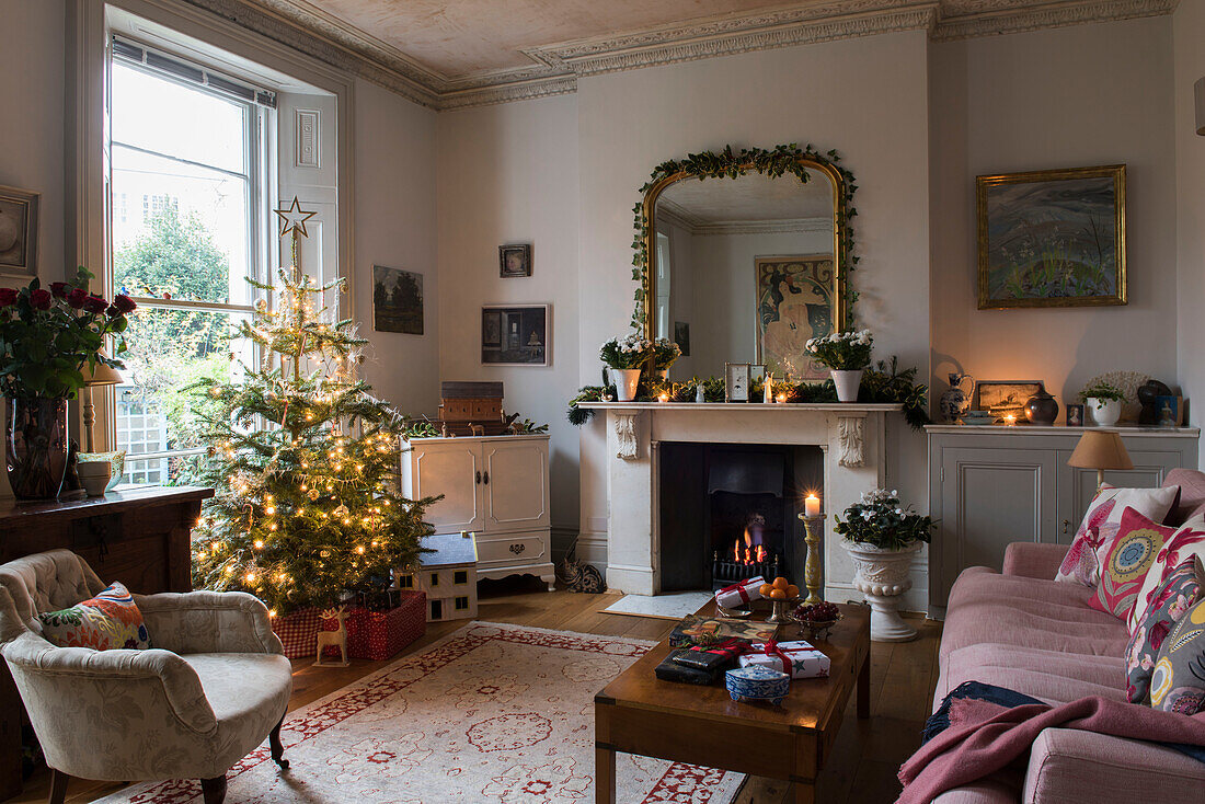 Lit Christmas tree in window of North London Victorian living room  England  UK