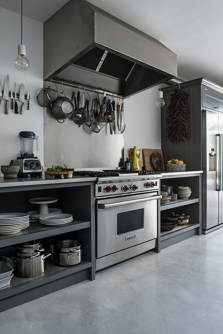 Utensil rack above stainless steel cooker with extractor in Whitstable kitchen   Kent  England  UK