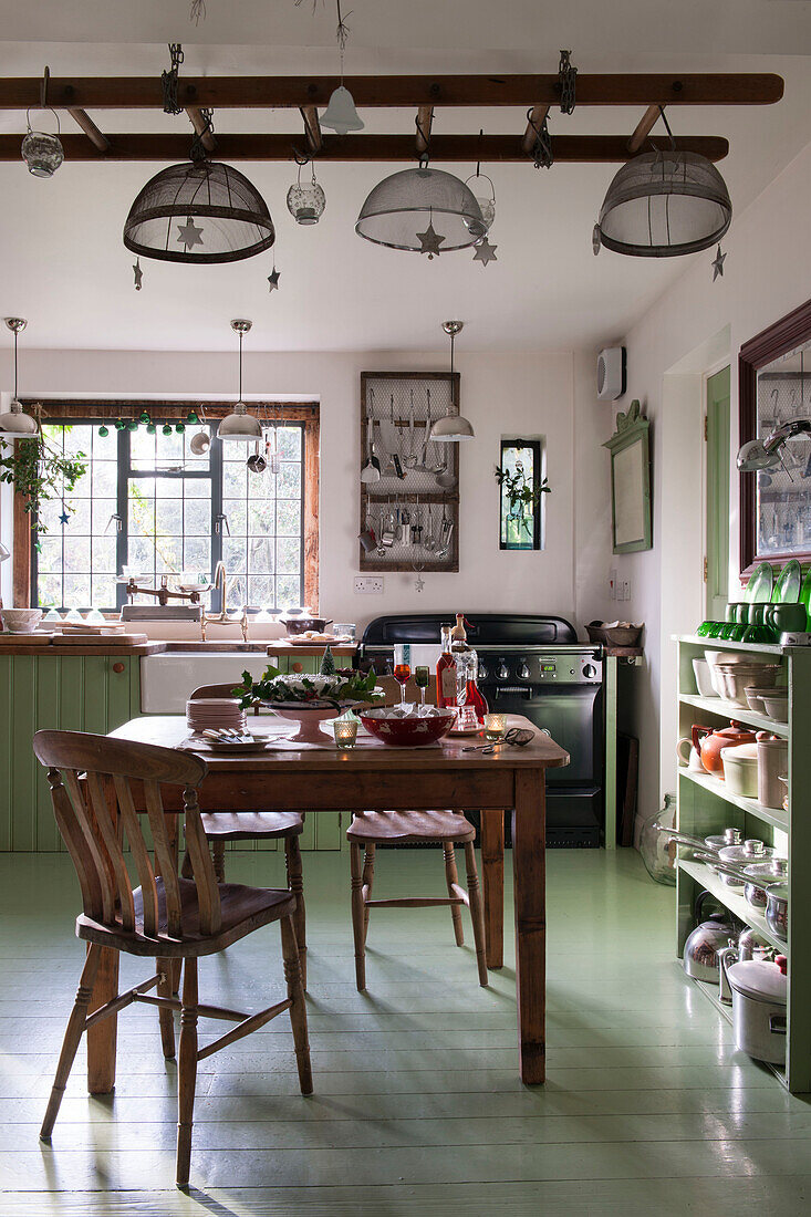 Holztisch und Stühle in der grünen Küche von Kilndown cottage Kent England UK