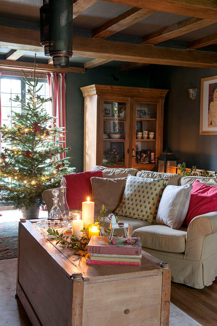 Beleuchteter Weihnachtsbaum und Sofa mit Kerzen im Wohnzimmer von Kilndown cottage Kent England UK