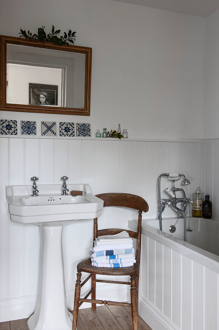 Gefaltete Handtücher auf einem Holzstuhl im Badezimmer mit Nut und Feder in Kilndown cottage Kent England UK
