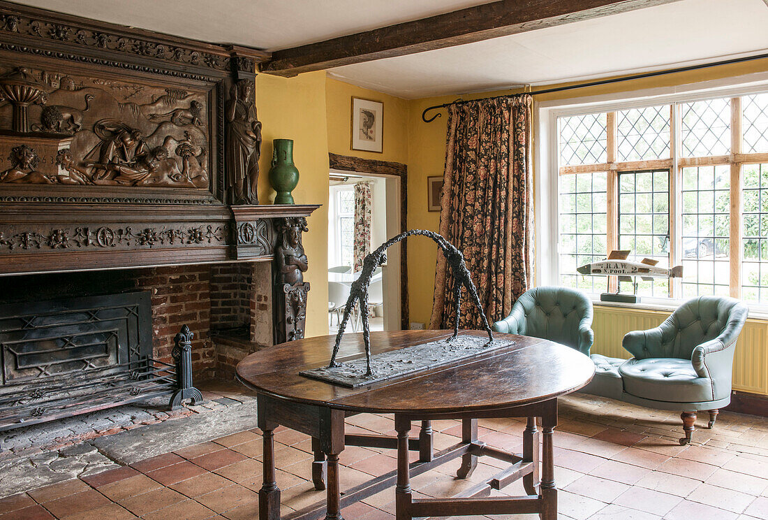 Carved fireplace with figurine on wooden folding table in terracotta tiled Suffolk farmhouse  England  UK