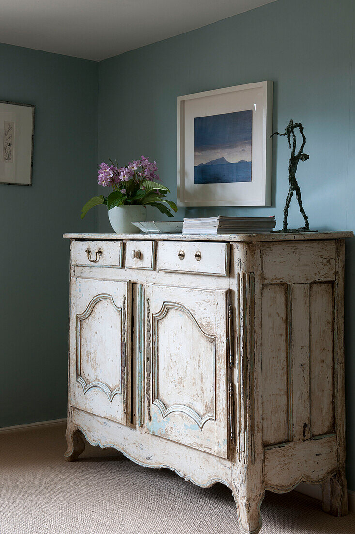 Antique side unit with houseplant and sculpture in light blue Suffolk bedroom  England  UK