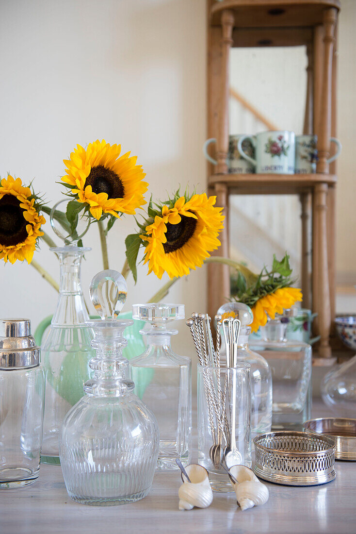 Sonnenblumen und Glaswaren mit Silberlöffeln in einer umgebauten Scheune in Norfolk aus dem 18