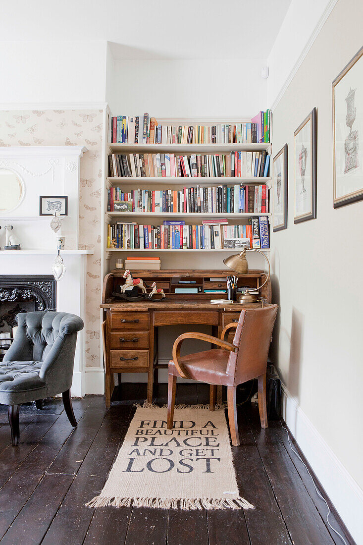 Bücherregale über einem Holzschreibtisch mit Lederstuhl und Fußmatte in einem Haus in Brighton, East Sussex, England, UK