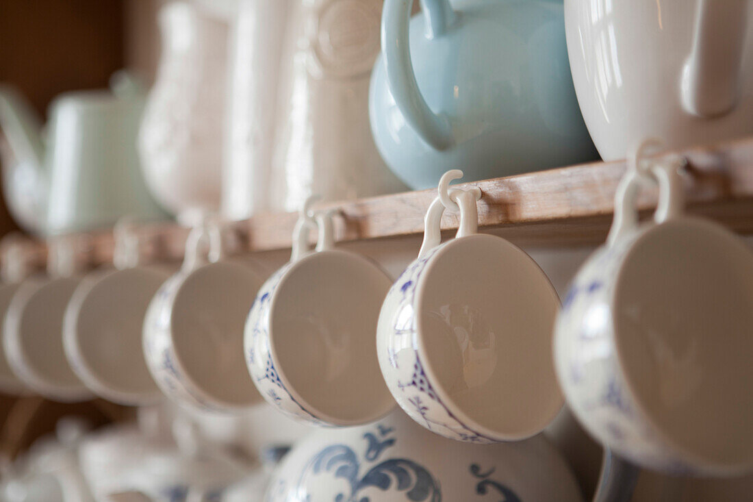 Teetassen hängen auf der Küchenkommode mit Keramikkrügen in einem Haus in Brighton, East Sussex, England, UK
