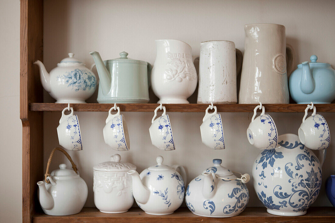 Collection of teacups and teapots on wooden dresser in Brighton home East Sussex England UK