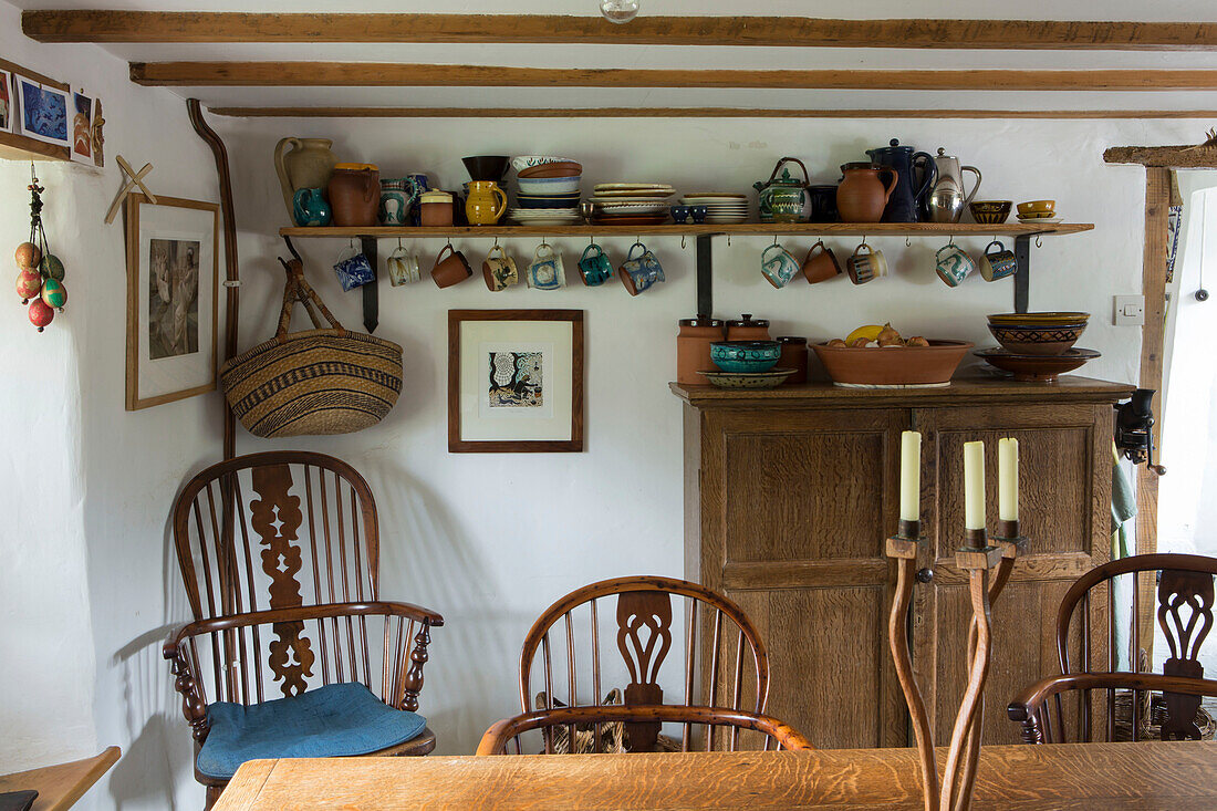 Geschirr auf offenem Regal mit Holzmöbeln in der Küche eines Cottage in Devon England UK