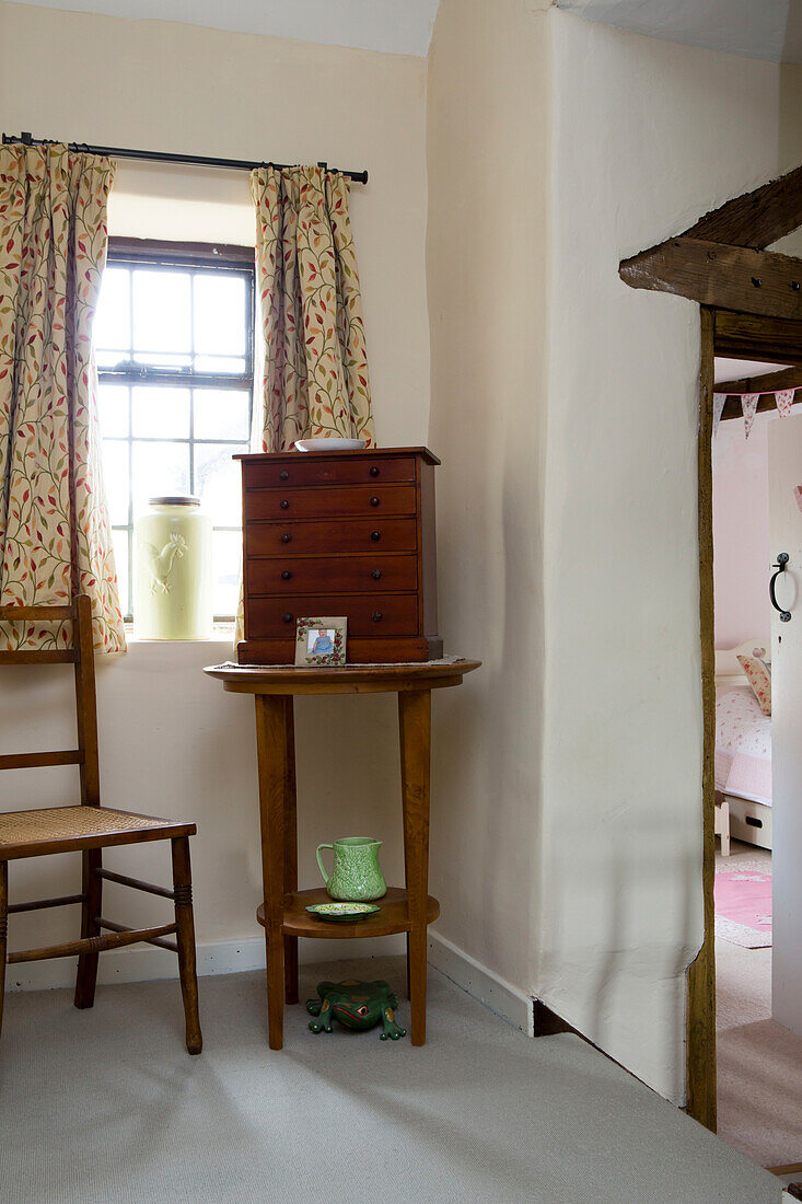 Wooden chest of drawers on side table at window in Amberley cottage West Sussex UK