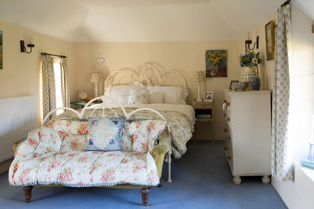 Weiße Metallbetten mit Steppdecken in einem Schlafzimmer mit blauem Teppichboden in Amberley cottage West Sussex UK