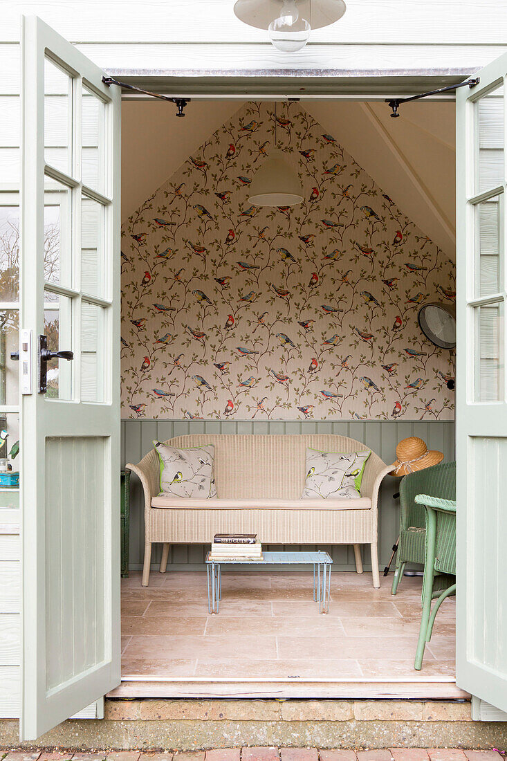 Blick auf Schilfrohrmöbel und gemusterte Tapeten im Sommerhaus von Amberley in West Sussex UK