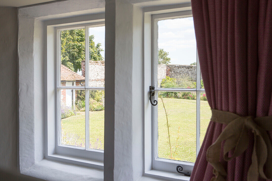 Blick auf den Garten durch weiß getünchte Fenster in einem Bauernhaus in Petworth, West Sussex, Kent