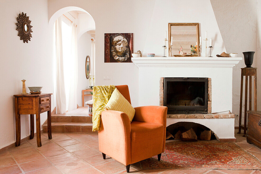 Oranger Sessel am Kamin in einem Terrakotta-Wohnzimmer, Castro Marim, Portugal