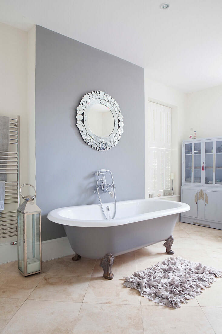 Runder Spiegel über einer freistehenden Badewanne in einem Haus in Amberley, West Sussex, England