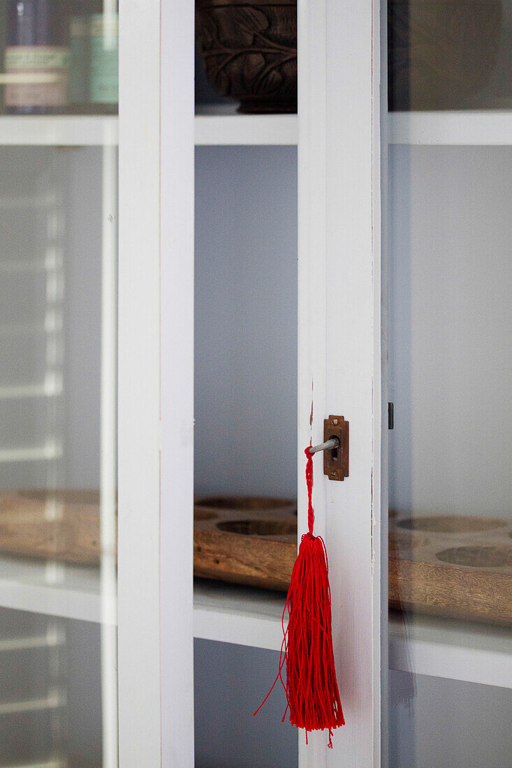 Red tassel on glass fronted bathroom cabinet in Amberley home, West Sussex, England, UK