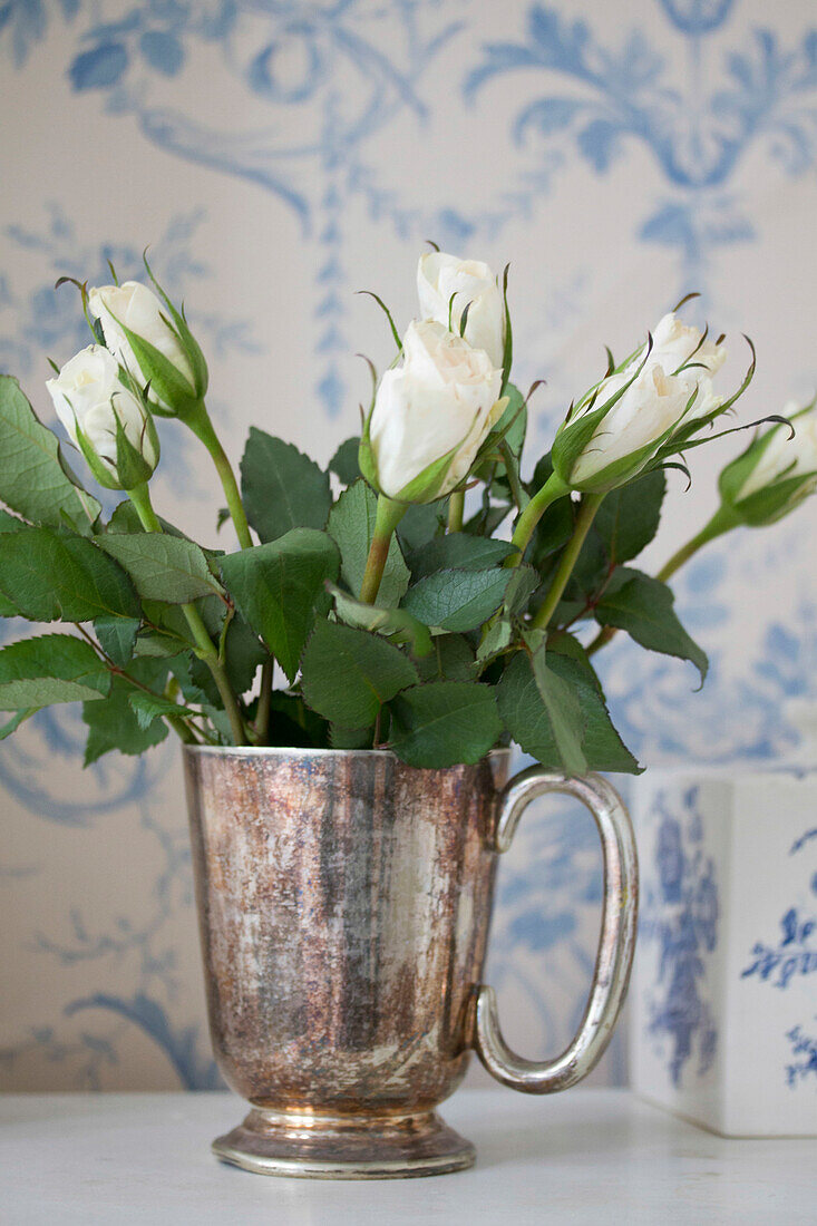 White roses in antique silver cup, Brighton home, East Sussex, England, UK