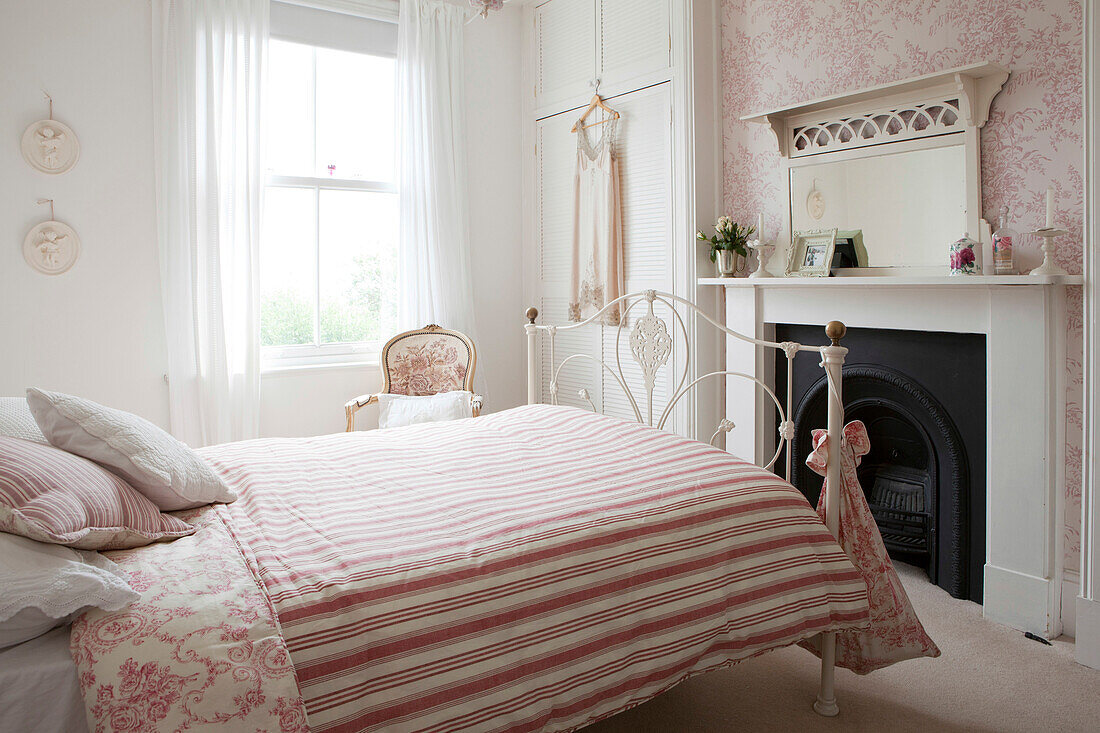 Negligee hangs at window in room with striped duvet on double bed in Brighton home, East Sussex, England, UK
